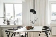 a Nordic dining space with a light-stained table, black wishbone chairs and a row of black pendant lamps is cool