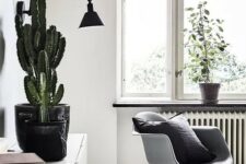 a Nordic room with a white Eames rocking chair, a white credenza with books and a cactus, a black sconce