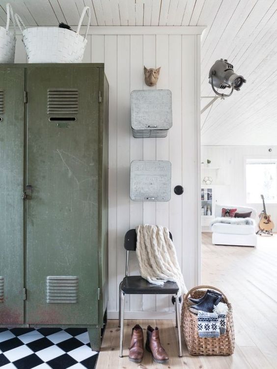 a Scandinavian entryway with a tiled and wooden floor, a green locker, a black chair and metal box-style shelves