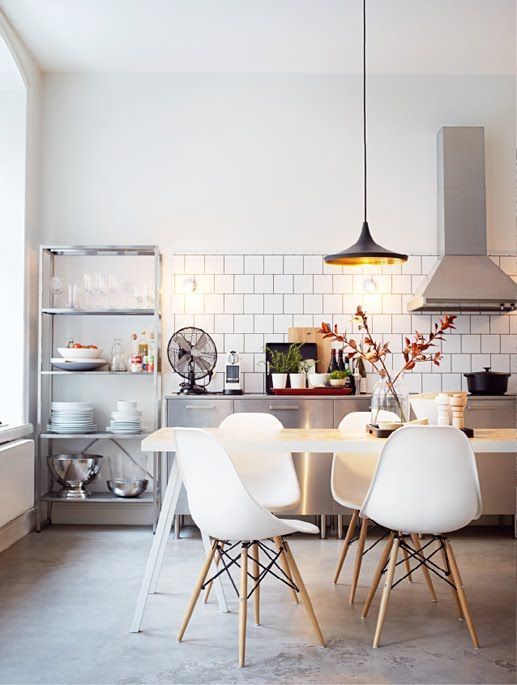 a Scandinavian kitchen with metal cabinets, a shelving unit, a white table, white Eames chairs and a pendant lamp