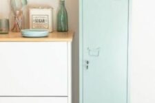 a Scandinavian kitchen with sleek white cabinets with stained countertops and a light mint blue locker and some potted plants