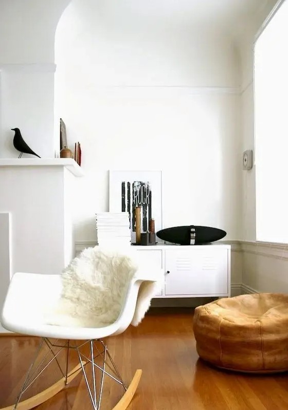 a Scandinavian nook with a locker, a white Eames rocker, a faux fur cover, a brown pouf and some pretty decor