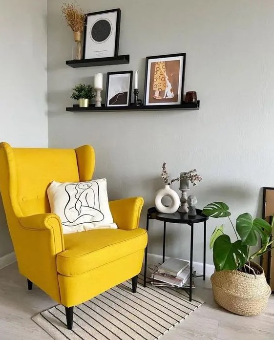 a Scandinavian nook with a yellow Strandmon chair, a striped rug, a black side table, black ledges with decor and a potted plant
