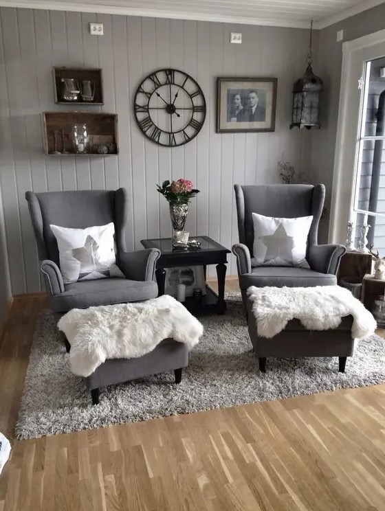 a Scandinavian sitting space with grey walls, box shelves, grey Strandmon chairs, ottomans, a grey rug and faux fur plus some decor