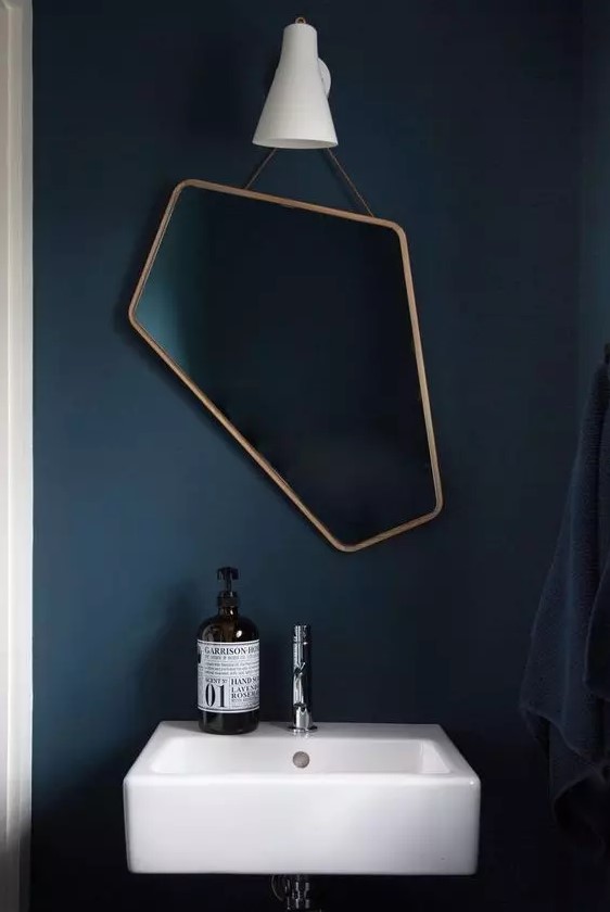 a beautiful and asymmetrical mirror in a copper frame is a catchy idea for a bathroom or a powder room, it will add interest to it