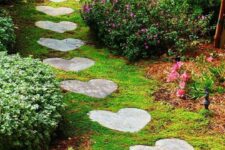 a beautiful green garden with heart-shaped stones that form a path, greenery and blooming bushes plus an elegant vintage bench