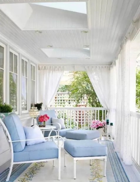 a beautiful porch done with light blue furniture and mosquito net curtains that can give privacy and save from bugs