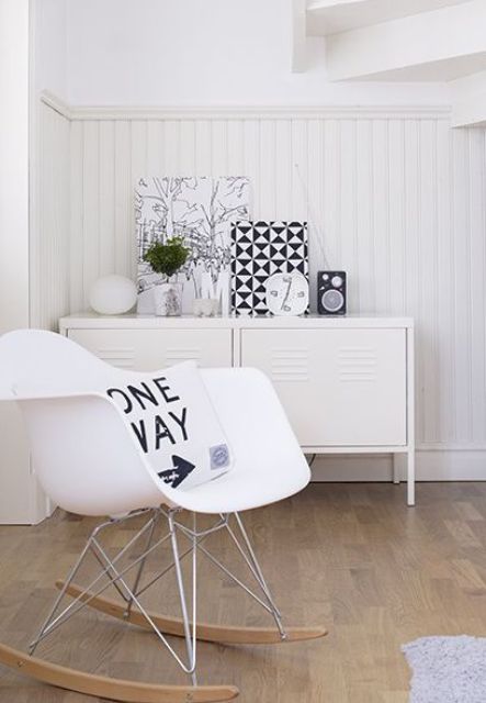 a black and white space with a white metal locker as a credenza, a white Eames rocking chair and some black touches