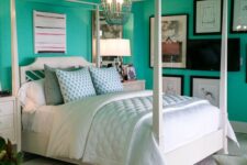 a bold turquoise bedroom with a white canopy bed and neutral bedding, a large gallery wall and a crystal chandelier