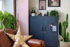 a bright eclectic space with a pink and navy locker, a leather chair, a bright printed rug, a gallery wall and potted greenery