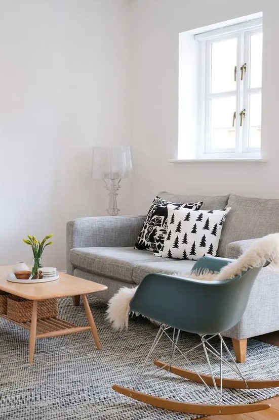 a calm Scandi living room with a grey sofa, a blue Eames rocker, a tiered coffee table and a grey rug