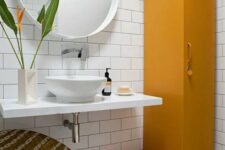 a catchy bathroom with white subway and hex tiles, a wall-mounted vanity and sink, a mustard locker and a woven round chair