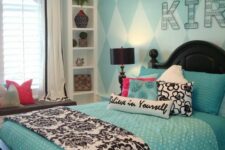 a catchy kid’s room with an accent turquoise geo wall, a black bed with turquoise bedding, a shelving unit and a windowsill bench