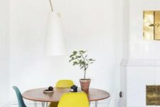 a chic Scandinavian dining space with a round table, colorful Eames chairs, a floor lamp and a hearth next to it