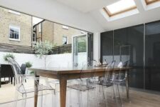 a chic and stylish dining room that can be opened to outdoors, with skylights, a stained dining table, ghost chairs is a lovely and elegant space