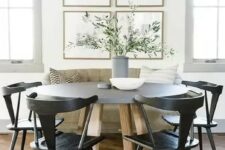 a chic modern farmhouse dining nook with a loveseat, a round table, black chairs, a chic gallery wall and greenery in a vase