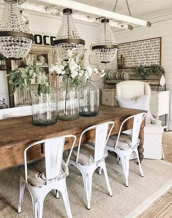a chic vintage farmhouse dining area with crystal chandeliers, a sign, a shabby chic buffet, a wooden table and metal chairs