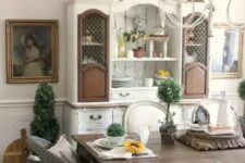 a classic farmhouse dining space with a shabby chic dining set, wicker chairs, a white and brown buffet and beautiful artworks