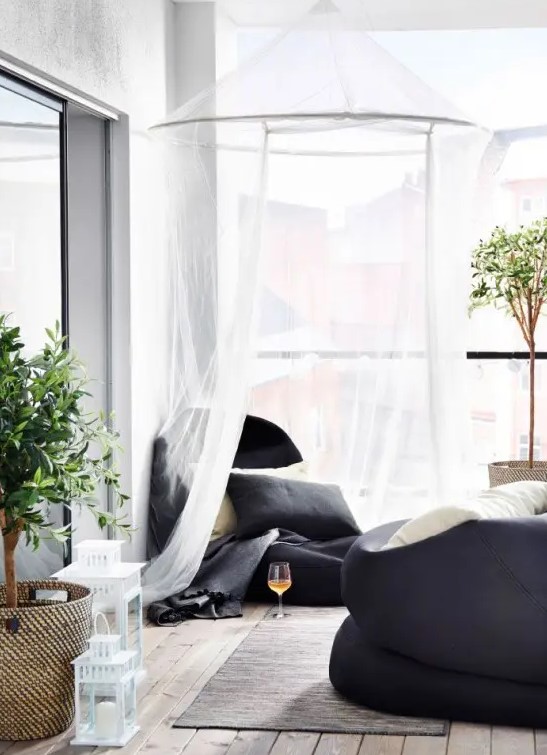 a contemporary balcony with black bean bag chairs and mosquito nets over them - both for decor and to avoid bugs