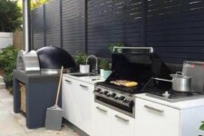 a contemporary outdoor barbecue area done in black and white, with a pizza oven and a grill plus storage cabinets