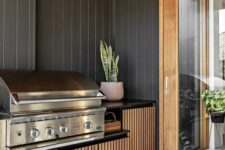 a contemporary outdoor bbq area with a large cabinet with a grill, a potted plant is a stylish and simple zone for cooking