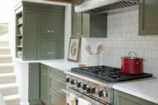 a cool olive green kitchen with shaker cabinets, a white square tile backsplash and white stone countertops, shiny knobs