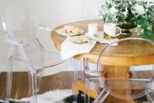 a cozy eating space with a round stained table, ghost chairs, a potted plant centerpiece is ultimate
