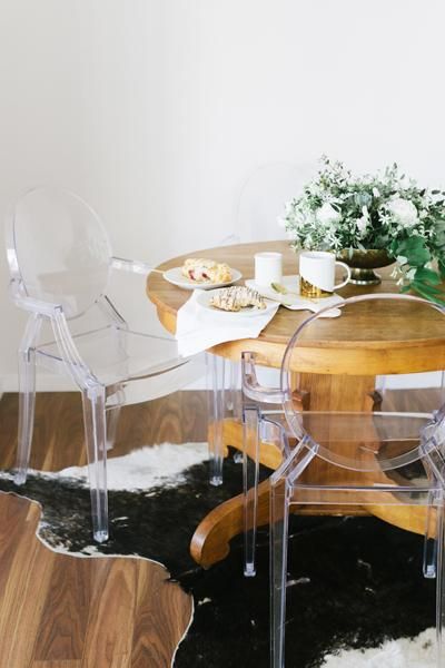 a cozy eating space with a round stained table, ghost chairs, a potted plant centerpiece is ultimate