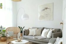 a cozy light-filled living room with a grey sofa, a rattan and a rocker chair, a hexagon coffee table and a woven pendant lamp