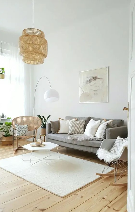 a cozy light filled living room with a grey sofa, a rattan and a rocker chair, a hexagon coffee table and a woven pendant lamp