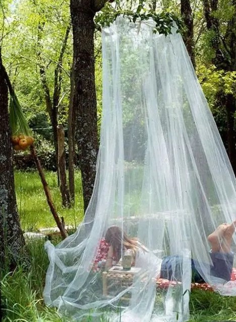 a cozy outdoor relaxation space with a daybed, pillows and a mosquito net - who needs more than that