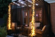 a cozy outdoor space with wicker furniture, blakc mosquito net, lights is a cool space to spend time in