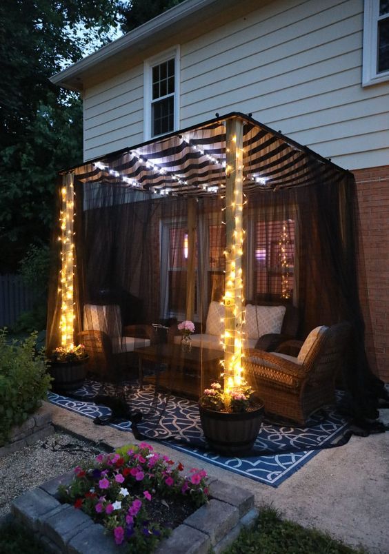 a cozy outdoor space with wicker furniture, blakc mosquito net, lights is a cool space to spend time in