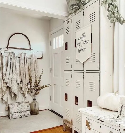 a creamy farmhouse space with a series of lockers, a white dresser, pumpkins, greenery and towels is cool