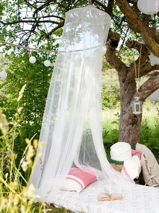 a daybed with a mosquito net over it, with pillows and lanterns to create your own outdoor oasis for relaxation