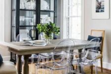 a farmhouse dining space with a black glass buffet, a stained table, ghost chairs and vintage ones, a jute rug