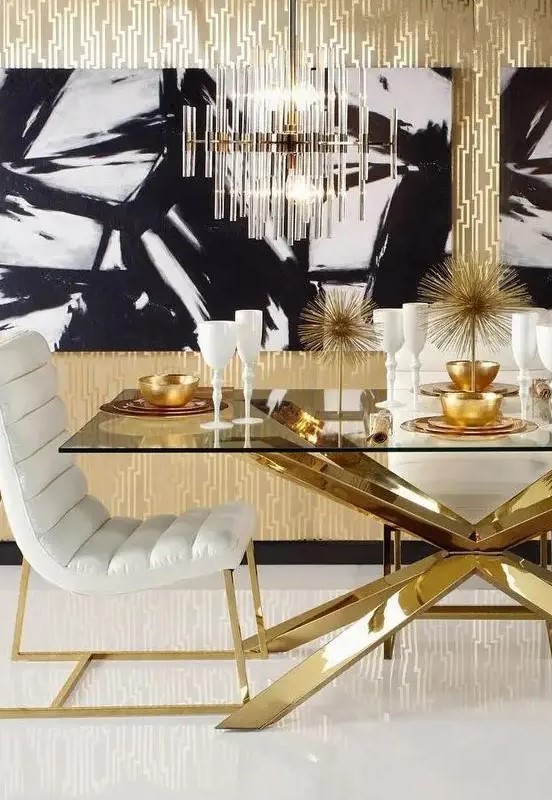 a glam black, white and gold dining room with a chic table with a glass tabletop and a gold base, white upholstered chairs and a crystal tube chandelier