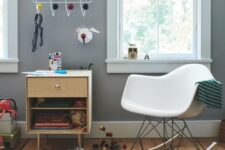 a kids’ space with a stained cabinet, a white rocking chair, some toys, a rack and kids’ drawings