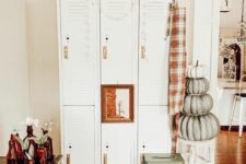 a lovely farmhouse space with a set of white lockers, a stained table, some crates and stools plus some rustic decor