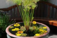 a mini pond of an oversized vintage porcelain urn with greenery, grasses and floating blooms is beautiful