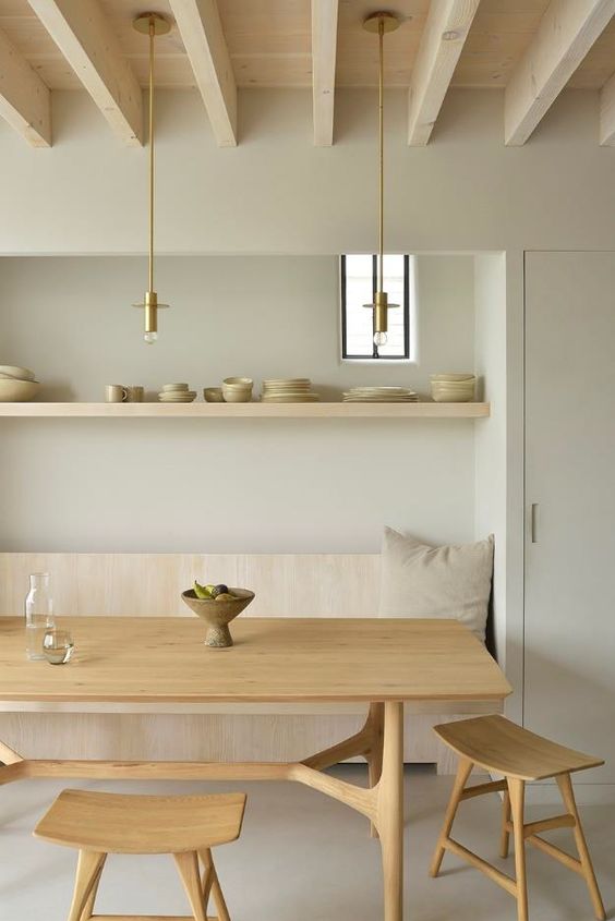 a minimal meets Japandi dining room with a wooden bench, a stained table adn stools, and open shelf and pendant bulbs