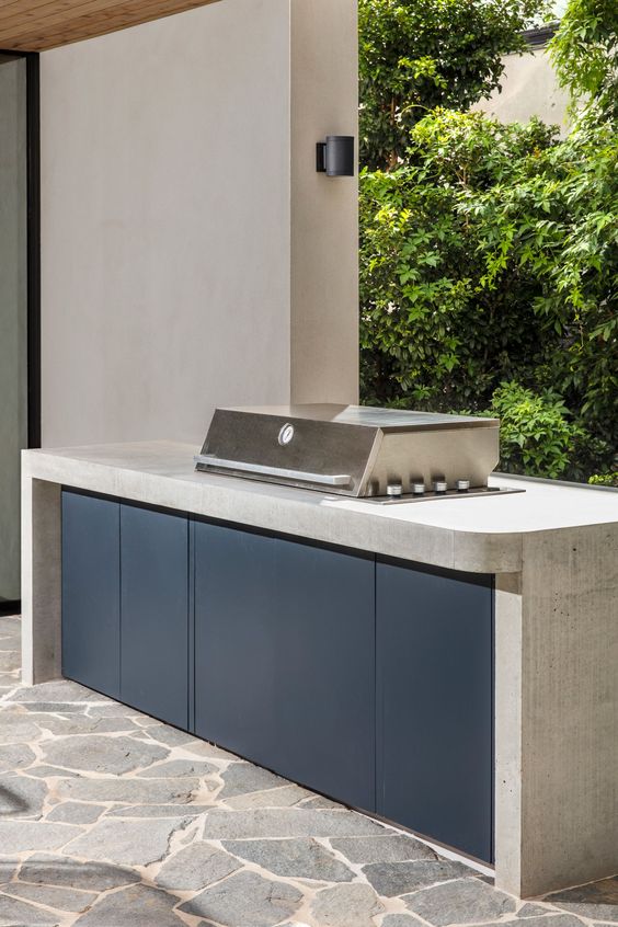 a minimalist bbq zone with a concrete kitchen island and a built-in grill plus sconces around is a chic and bold idea