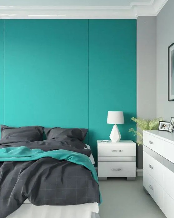a minimalist bedroom with a turquoise paneled accent wall, a white bed with grey bedding, a white dresser and a nightstand
