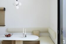 a minimalist corner dining space with a corner upholstered bench, an oval table, a catchy pendant lamp