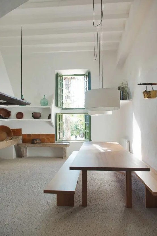 a minimalist dining space with a large stained table and benches, pendant lamps and nothing else is super cool