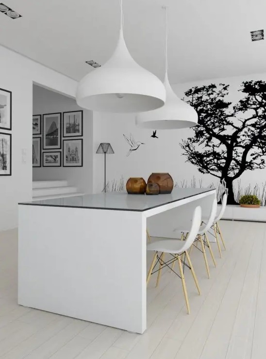 a minimalist dining space with a wall mural, a white dining table and chairs, large pendant lamps and a black and white gallery wall