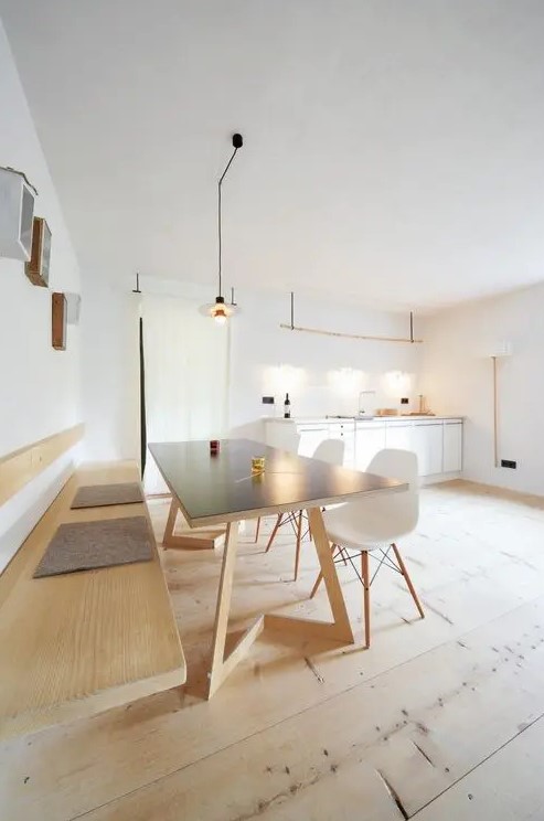 a minimalist meets Scandinavian dining space with a wall mounted bench, a comfy table, white Eames chairs, box shelves on the wall