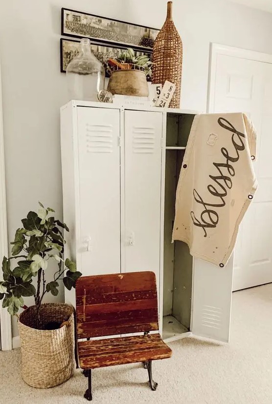 a neutral farmhouse space with creamy lockers, a shabby chic chair, artwork, potted greeneyr and a woven lamp