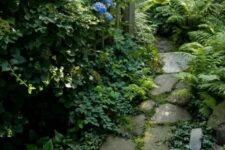 a relaxed stone garden path with greenery in between and lush foliage growing around for a calming look