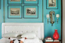 a retro bedroom done with turquoise walls, a white bed with neutral bedding, a stained nightstand and a red vase